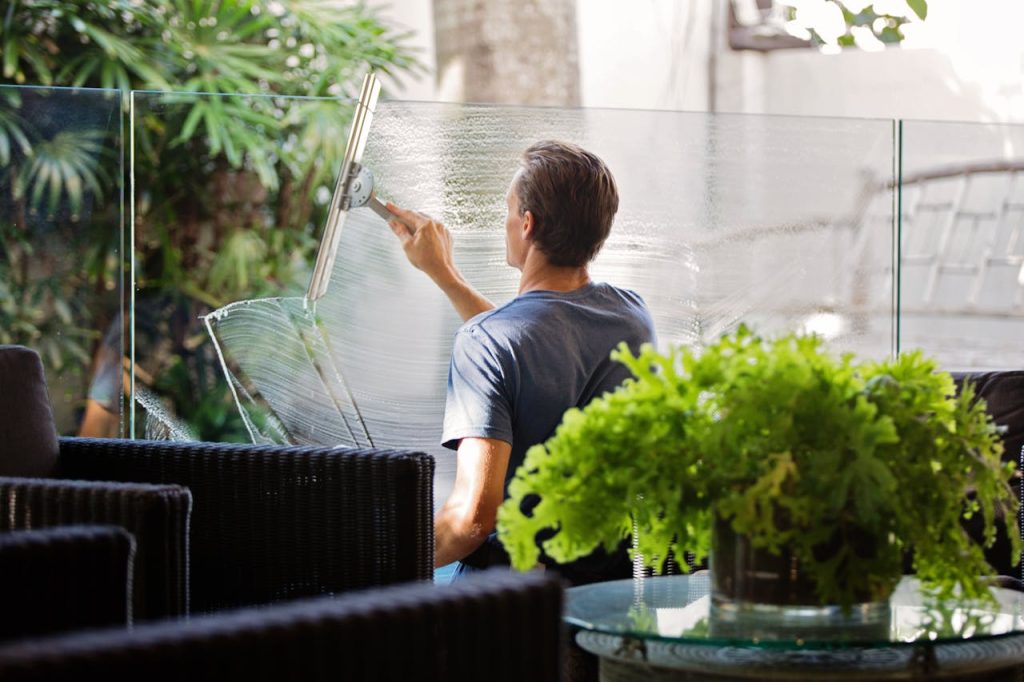 man-in-gray-shirt-cleaning-clear-glass-wall-near-sofa-713297 Man in Gray Shirt Cleaning Clear Glass Wall Near Sofa